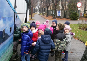 Widok na grupę dzieci wsiadających do autokaru.